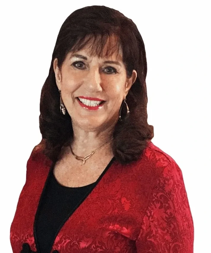 Women with dark hair, wearing a red patterned blazer and a black top, smiling at the camera.