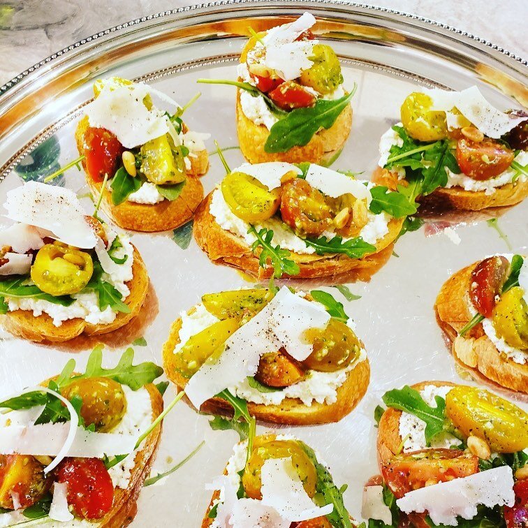 Tomato and ricotta toasts with Parmesan, arugula, and pine nuts. #crostini #tomatoes #yegcatering #yegfood #yegevents