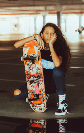 Teenager with a skateboard looking thoughtful.