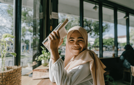 Woman in hijab holding a book.