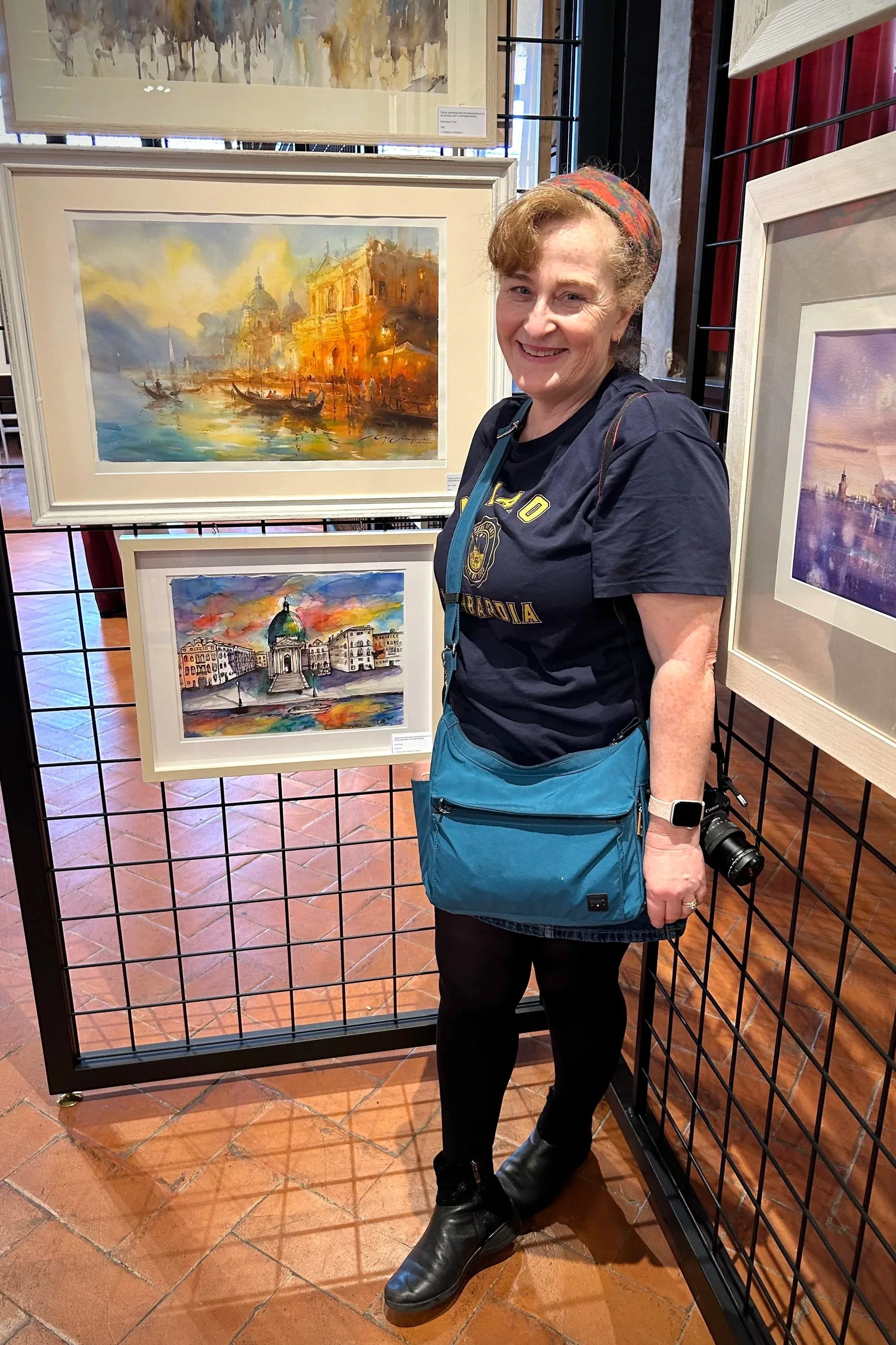 Cate Rose standing by her painting being exhibited in Venice