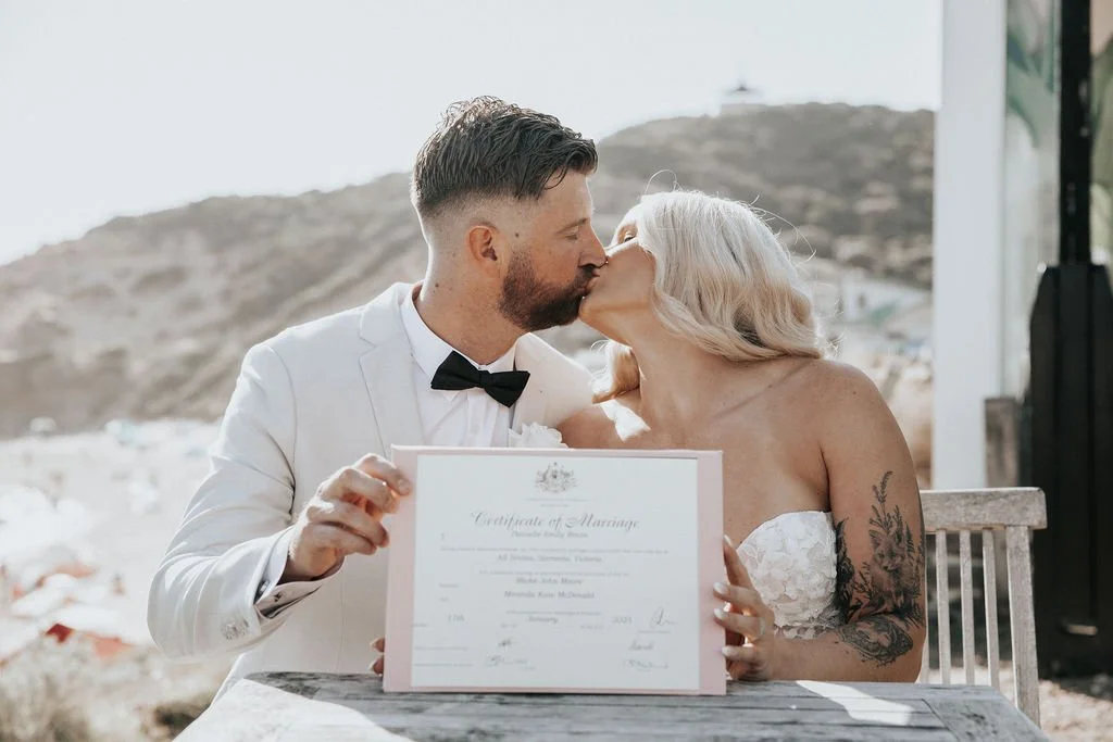 Blake and Miranda kissing while holding their marriage certificate