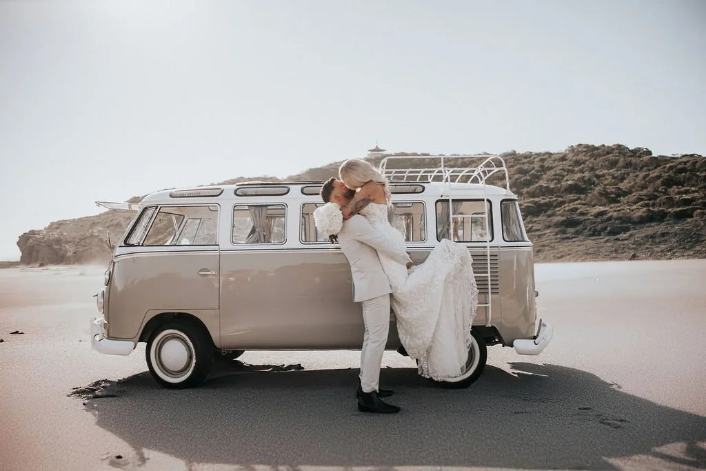 Blake and Miranda embracing beside a vintage Kombi during their wedding portraits