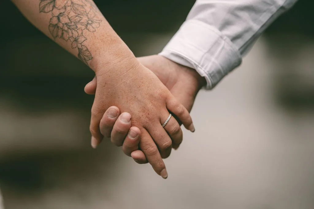 Close-up of Bronti and Juan-Ruan holding hands with wedding rings visible