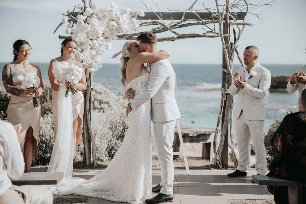 Blake and Miranda kissing during their seaside wedding ceremony