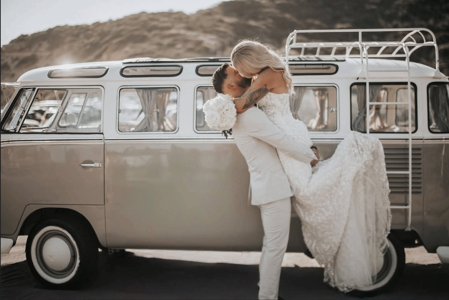 Bride and groom embracing beside a vintage wedding van