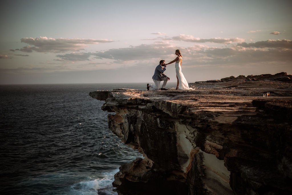 Erica and Chris posing together on a coastal cliff during their wedding portraits