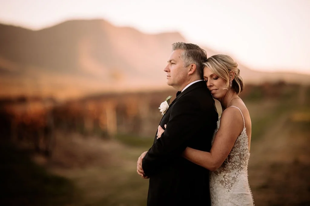 Brendon and Kate embracing during sunset wedding portraits in the vineyard