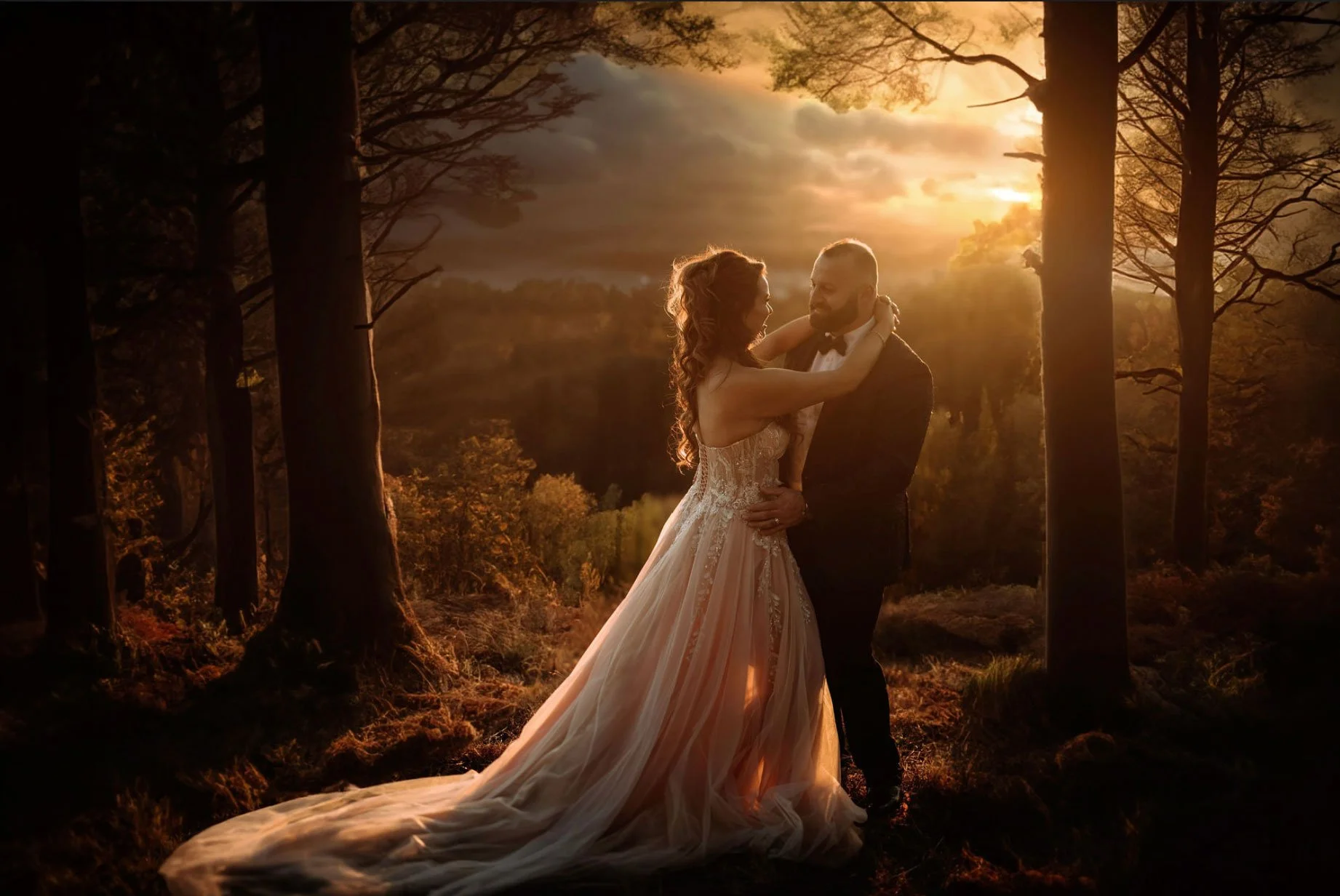 Bride and groom embracing at sunset among the trees on their wedding day