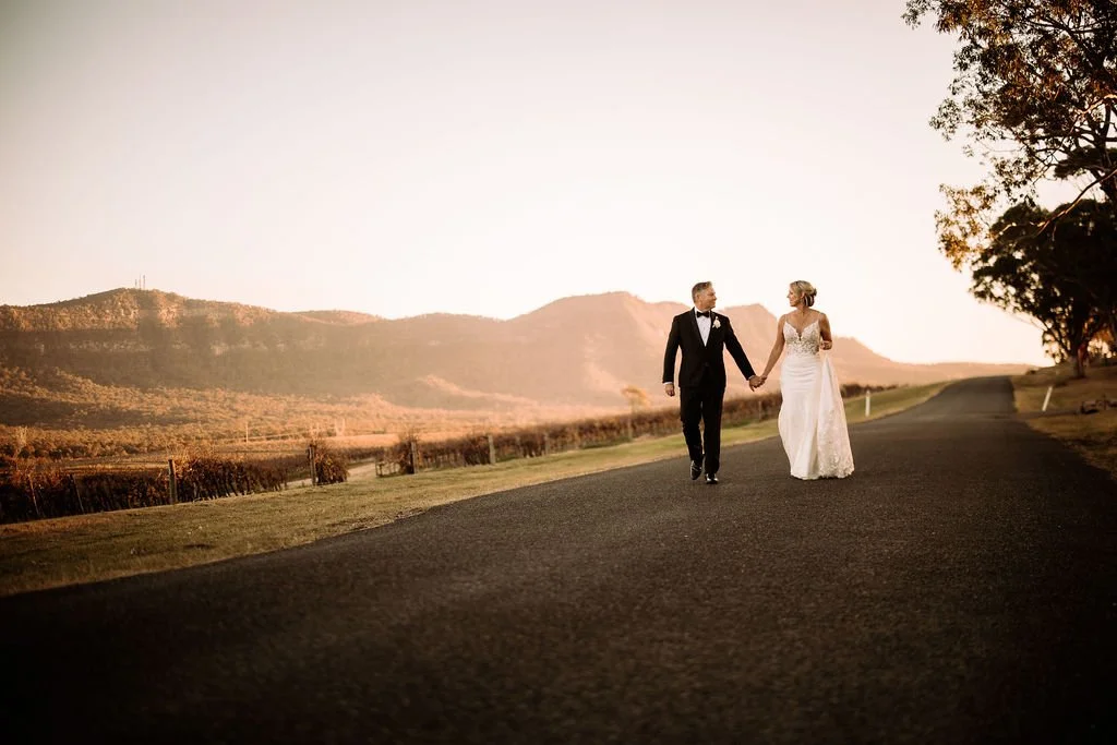 Brendon and Kate walking together along a country road during their wedding portraits