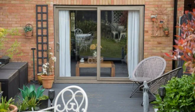 Outdoor garden patio with potted plants, metal chairs, and a sliding glass door leading to an indoor area.