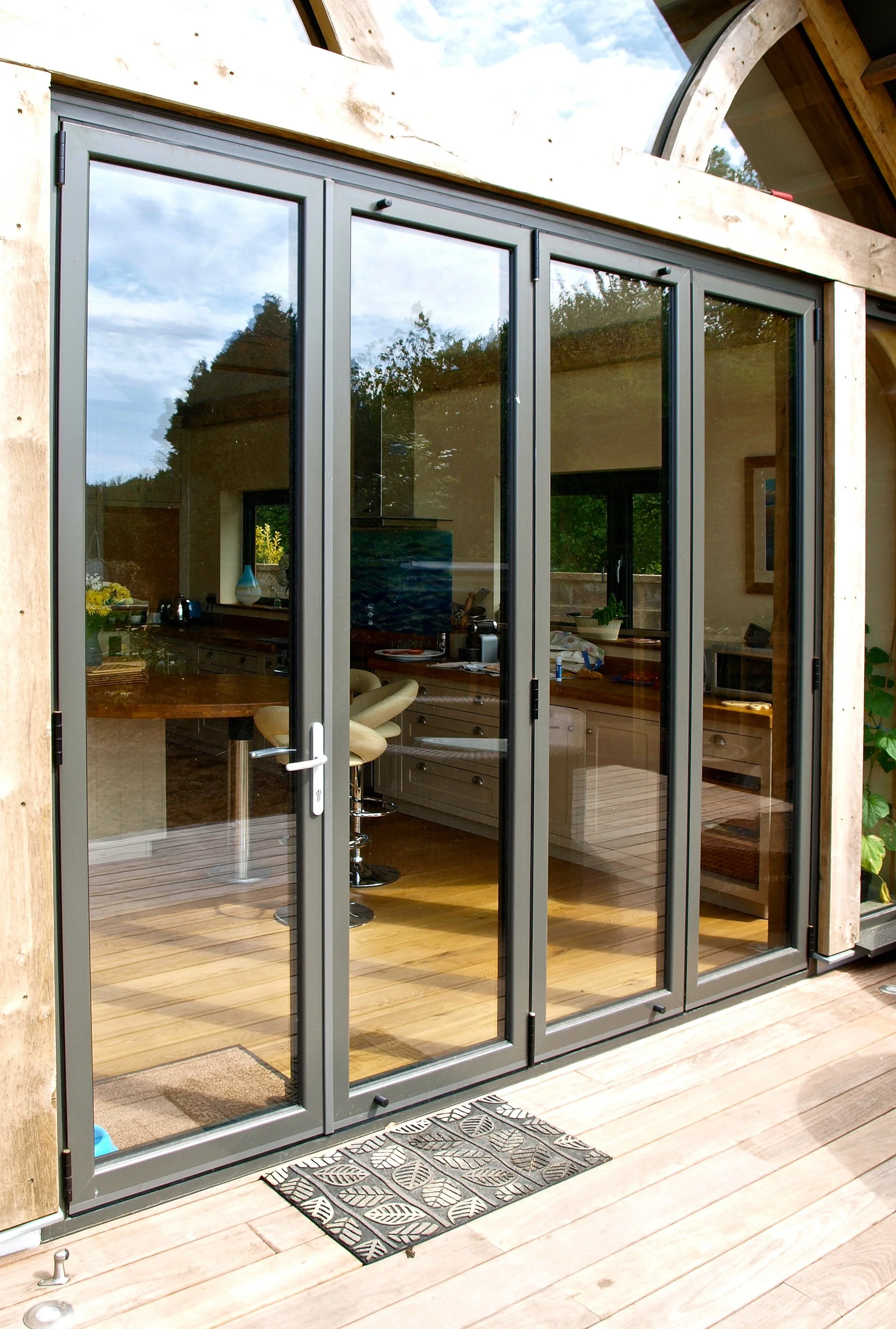 Sliding glass doors leading into a kitchen with a wooden countertop and bar stools, viewed from a wooden deck outside.