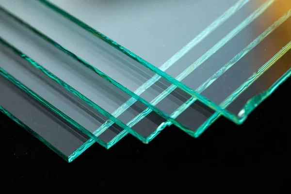 A close-up of stacked single pane glass sheets with reflections.