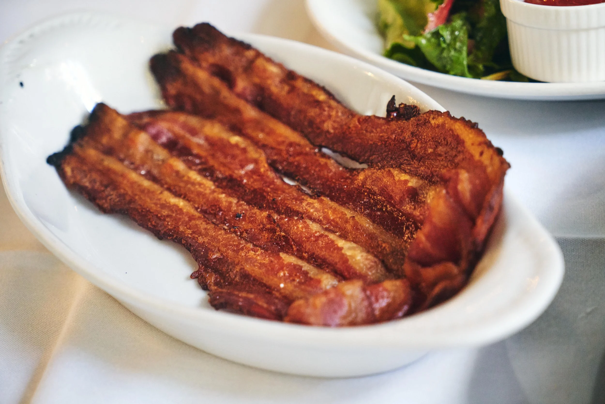 Bacon strips on a white ceramic dish.