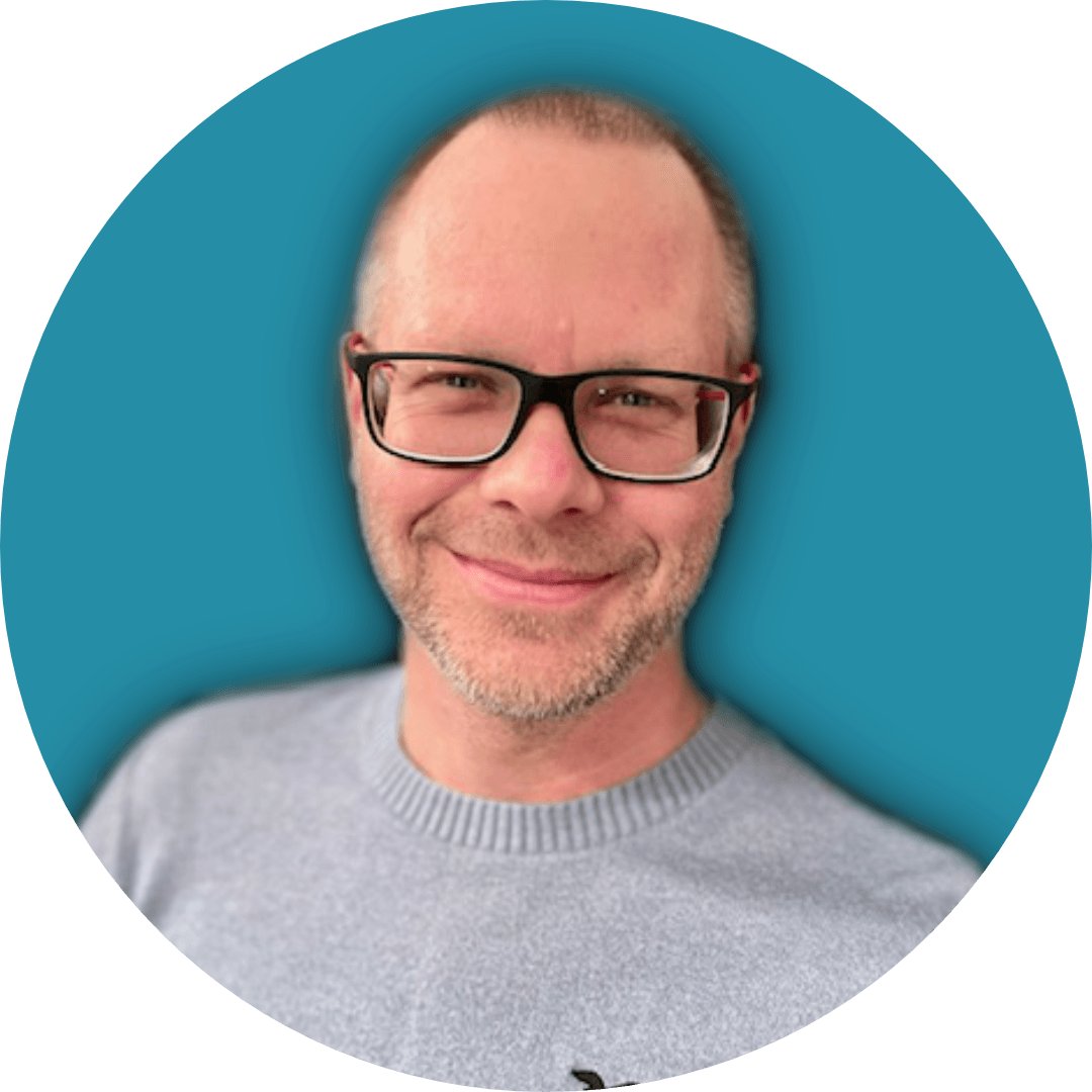 Garth Pendleton-Brown with glasses smiling against a blue background.