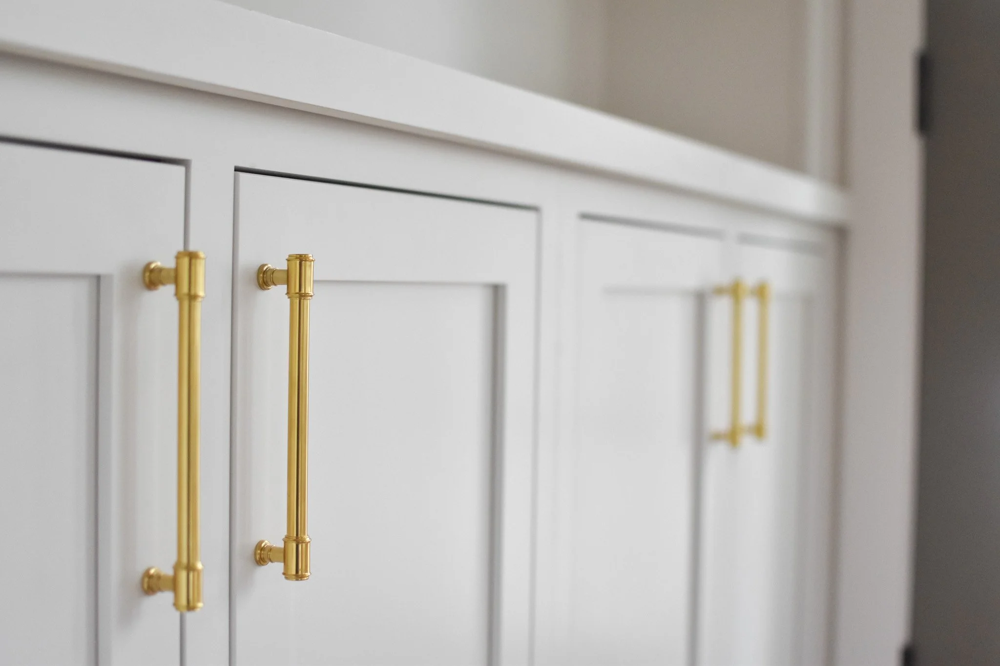 Close-up of white cabinet with gold handles.