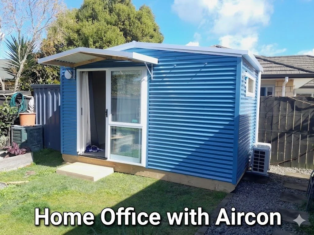 Blue home office shed with air conditioning unit outside, sliding glass door, and small steps leading to the entrance, in a backyard.
