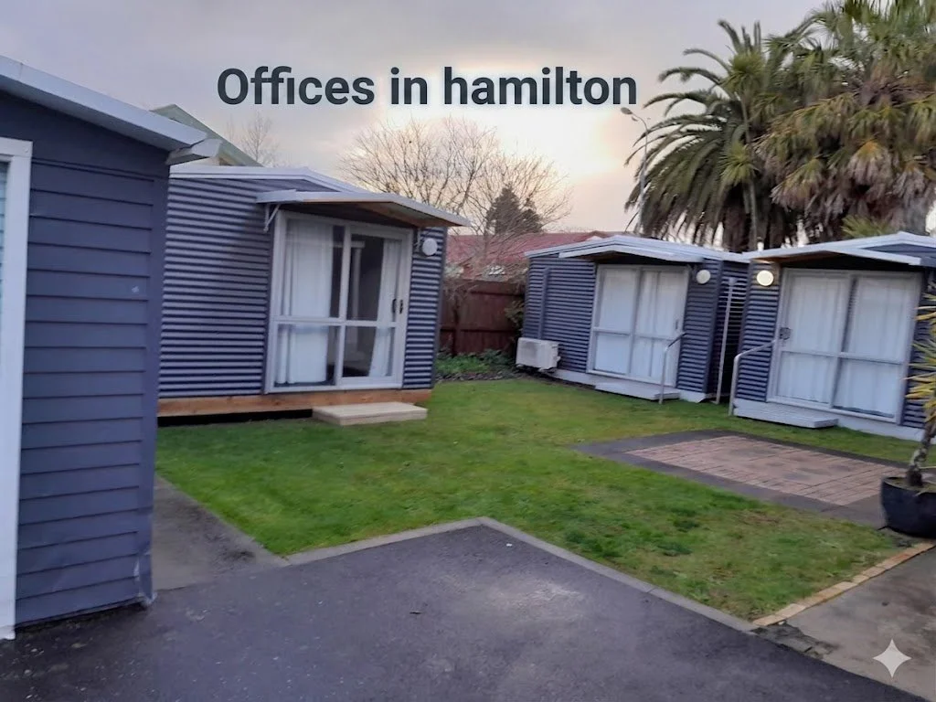 Small office cabins in a backyard with a lawn and paved patio, trees and a cloudy sky in the background, and the text 'Offices in hamilton' at the top.