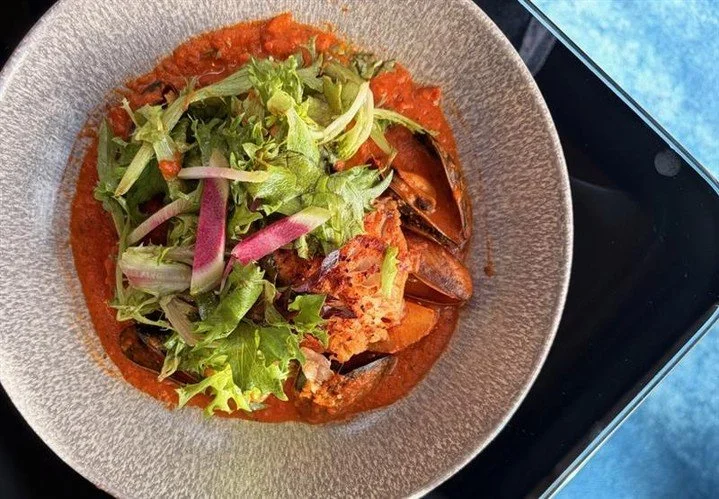 Straight from the coast to our NEW menu 🌊 Half Moon Bay rock cod simmered with mussels, preserved tomatoes, red peppers, garlic, onions, and Yukon Gold potatoes, finished with a pop of fresh micro-greens.