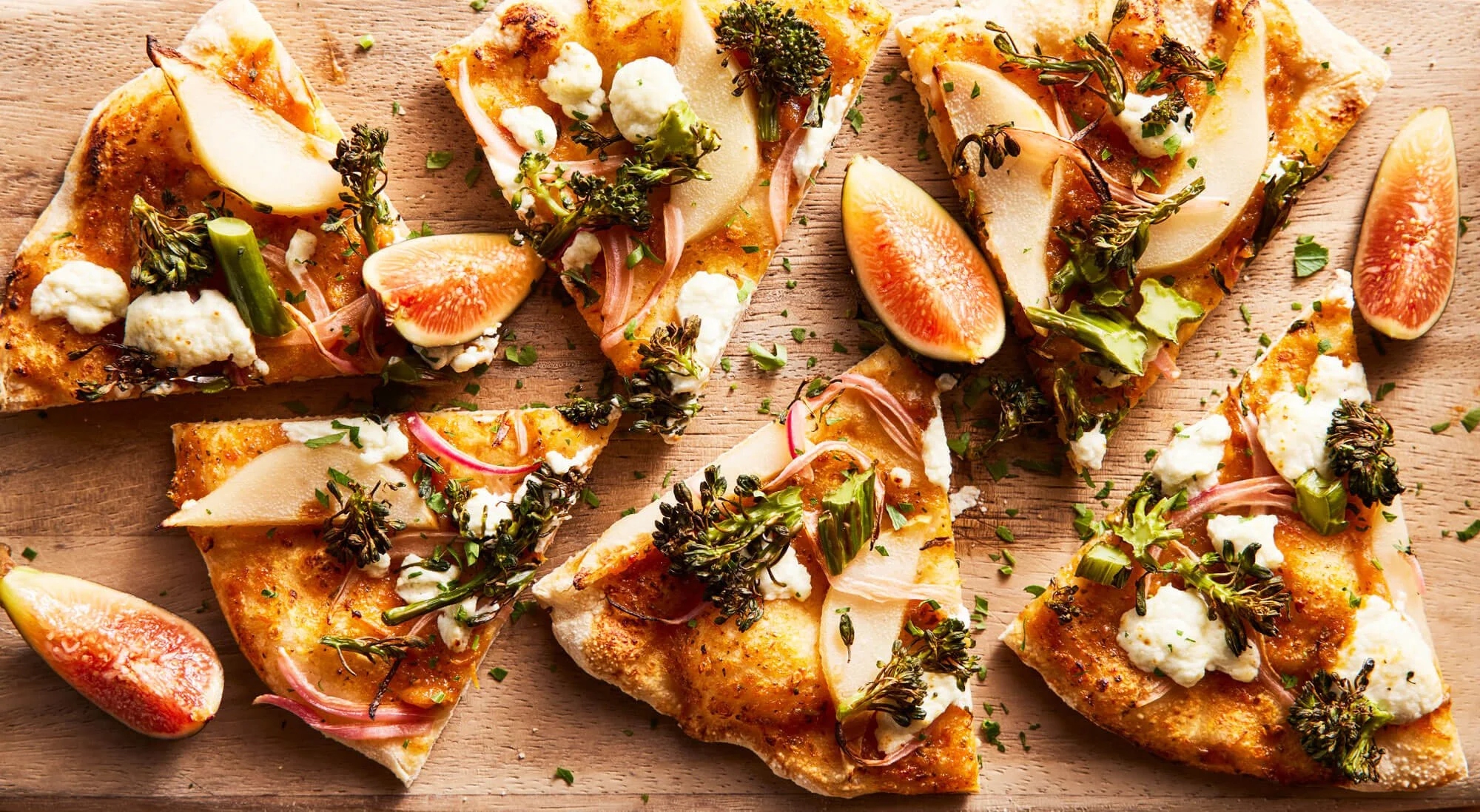 Seasonal pizza with broccolini, pear, butternut squash marinara sauce, goat cheese, pickled red onions, arugula