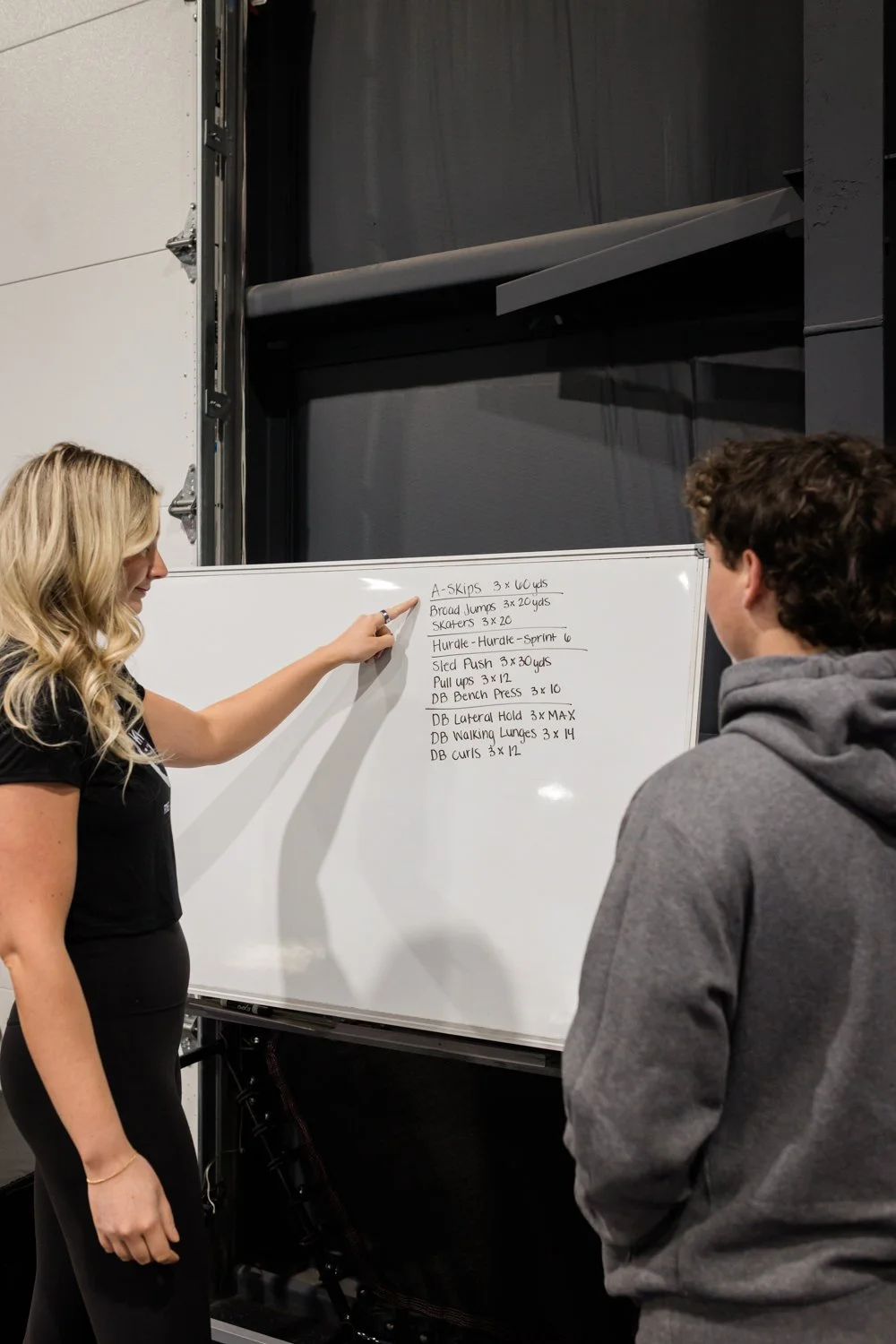 trainer explaining workout plan using whiteboard in gym
