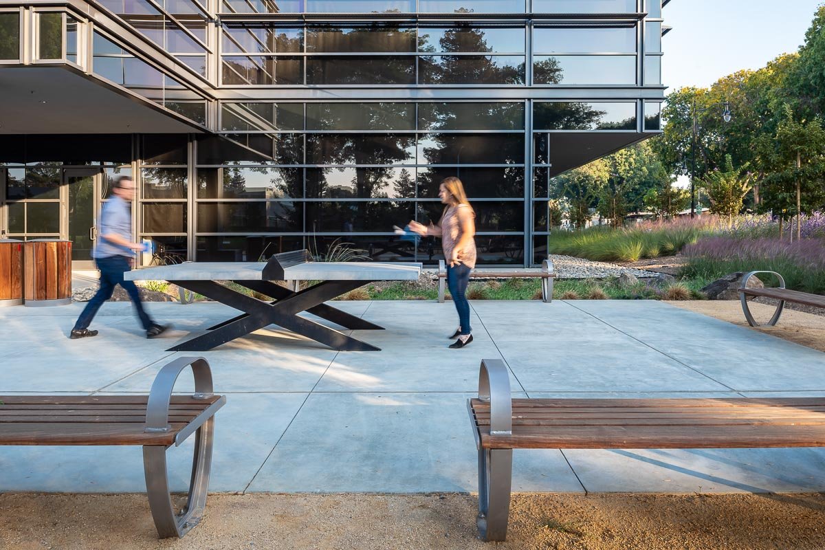 man and woman playing ping pong on a modern concrete ping pong table