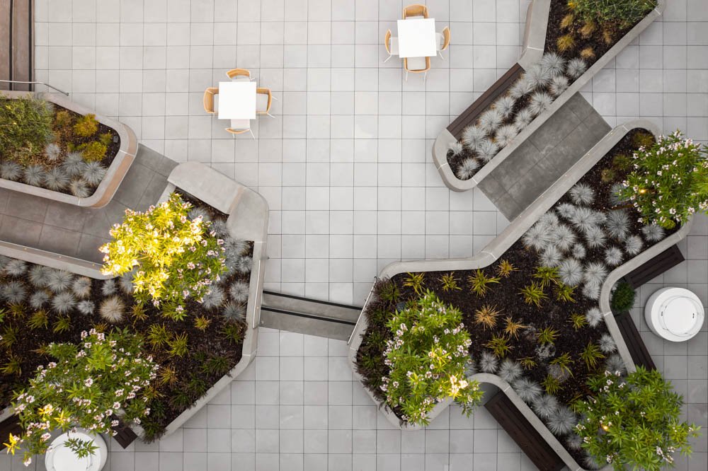 bird's eye abstract view of a modern courtyard with concrete planters and white tables.