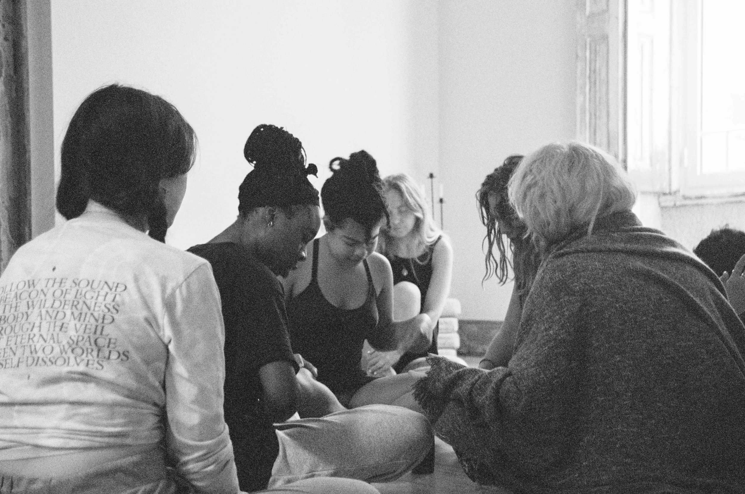 Group of people sitting on floor in meditation or discussion circle.