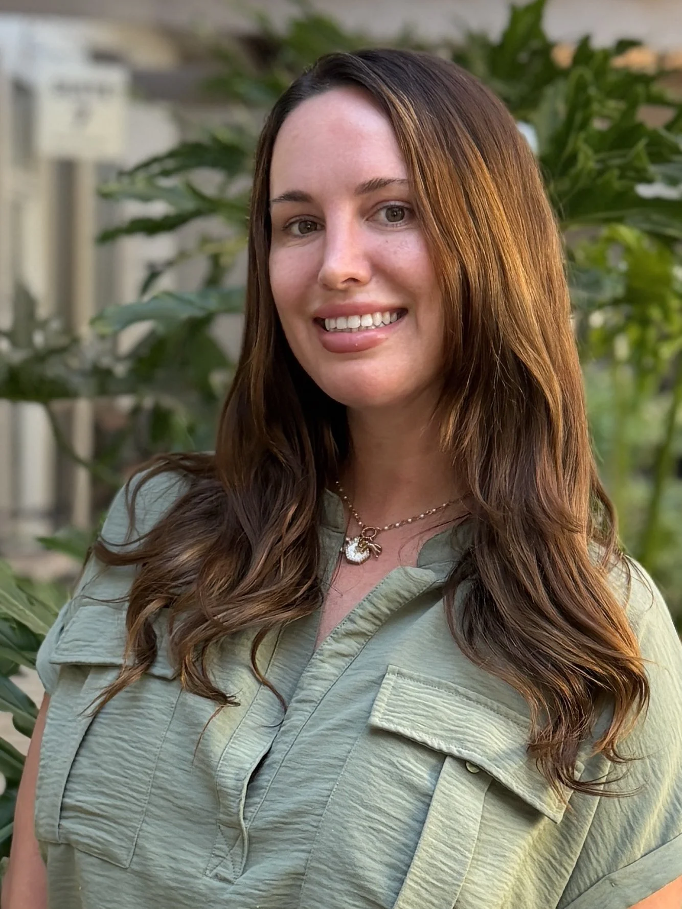 Nurse Practitioner, Heather Dollar smiling outside in front of greenery 