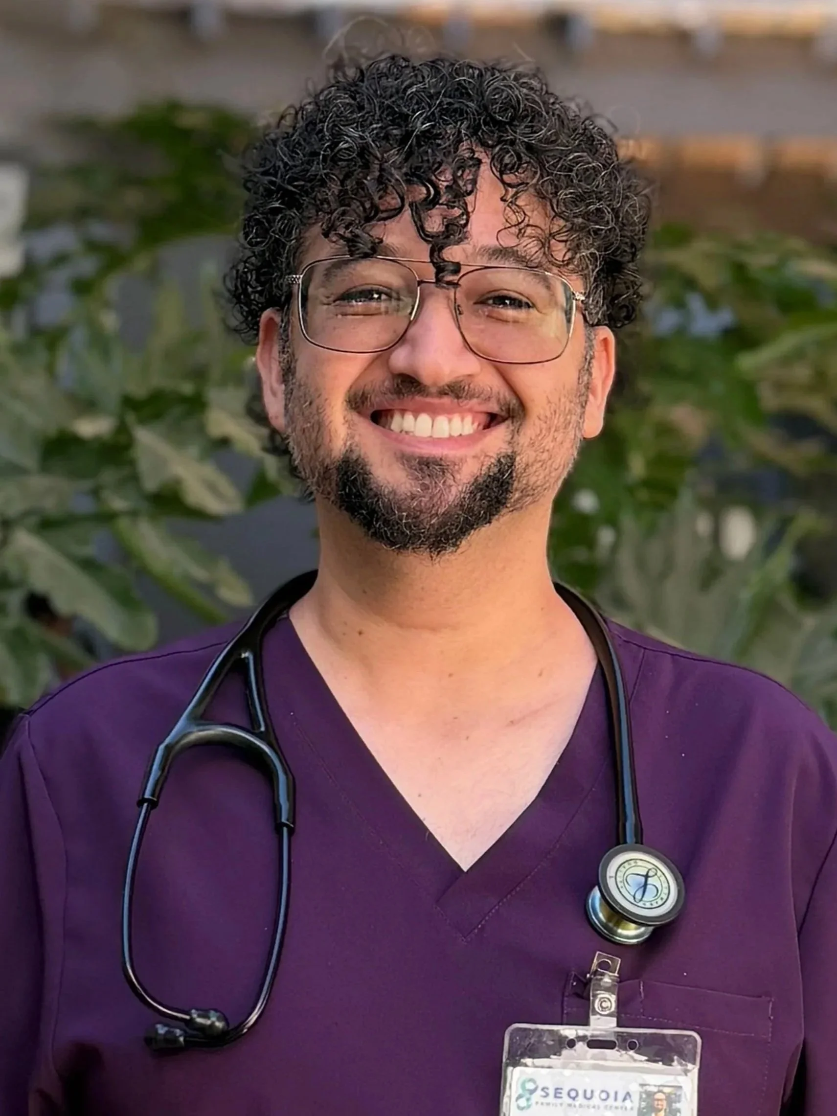 Physician Assistant Certified provider, Fernando Hernandez smiling in front of greenery