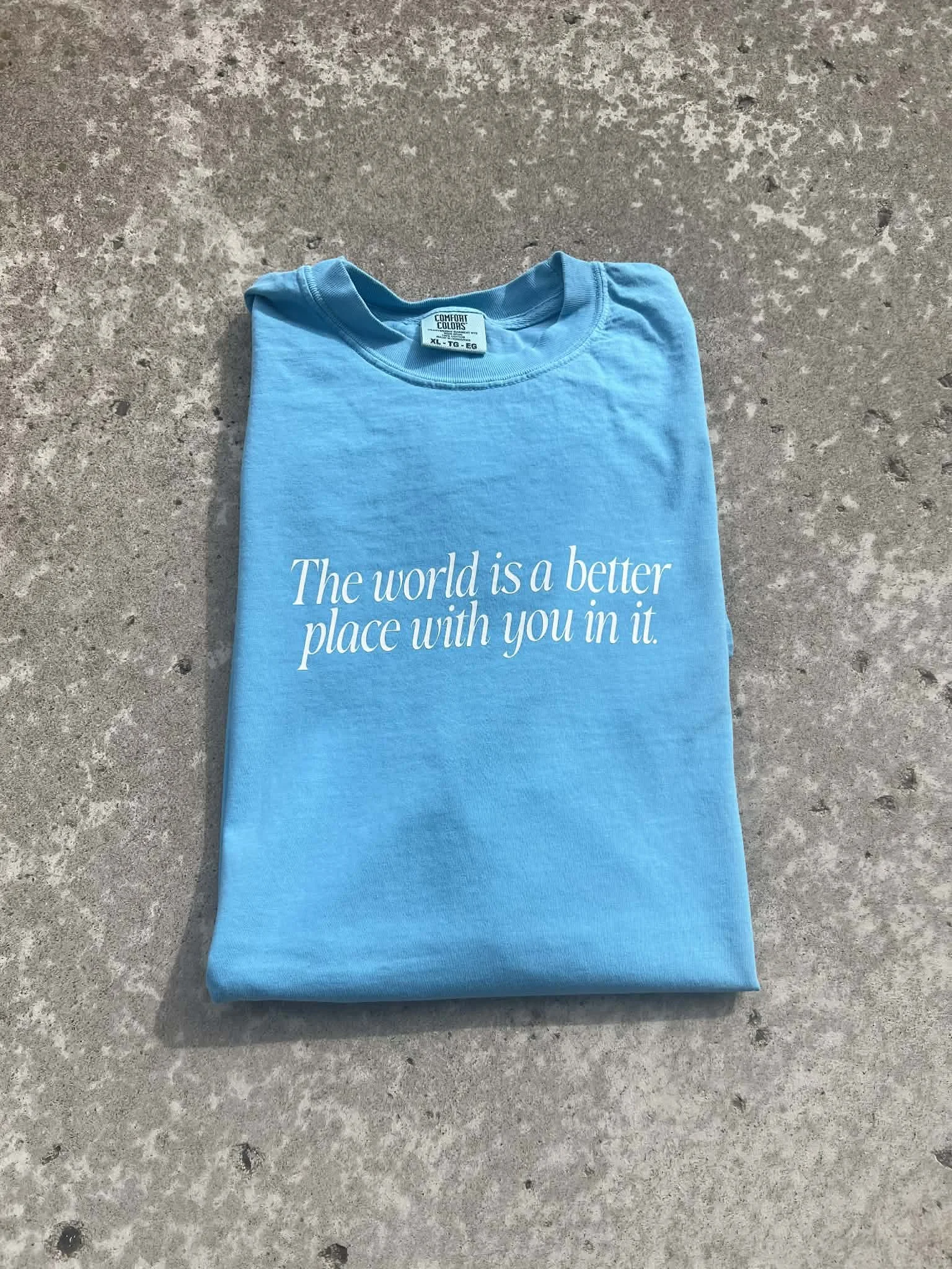 Light blue tee that has white text reading 'the world is a better place with you in it'