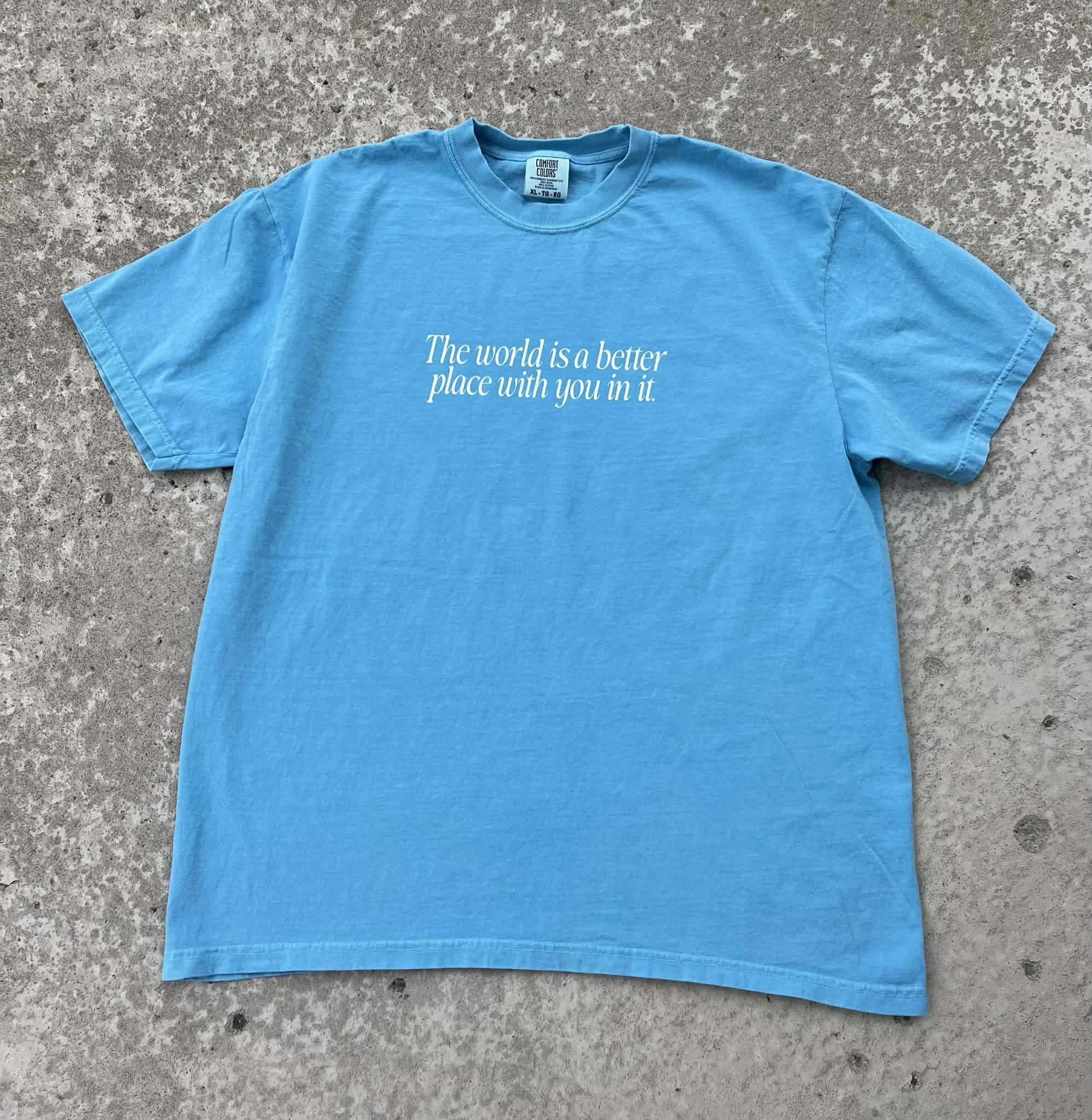 Light blue tee that has white text reading 'the world is a better place with you in it'