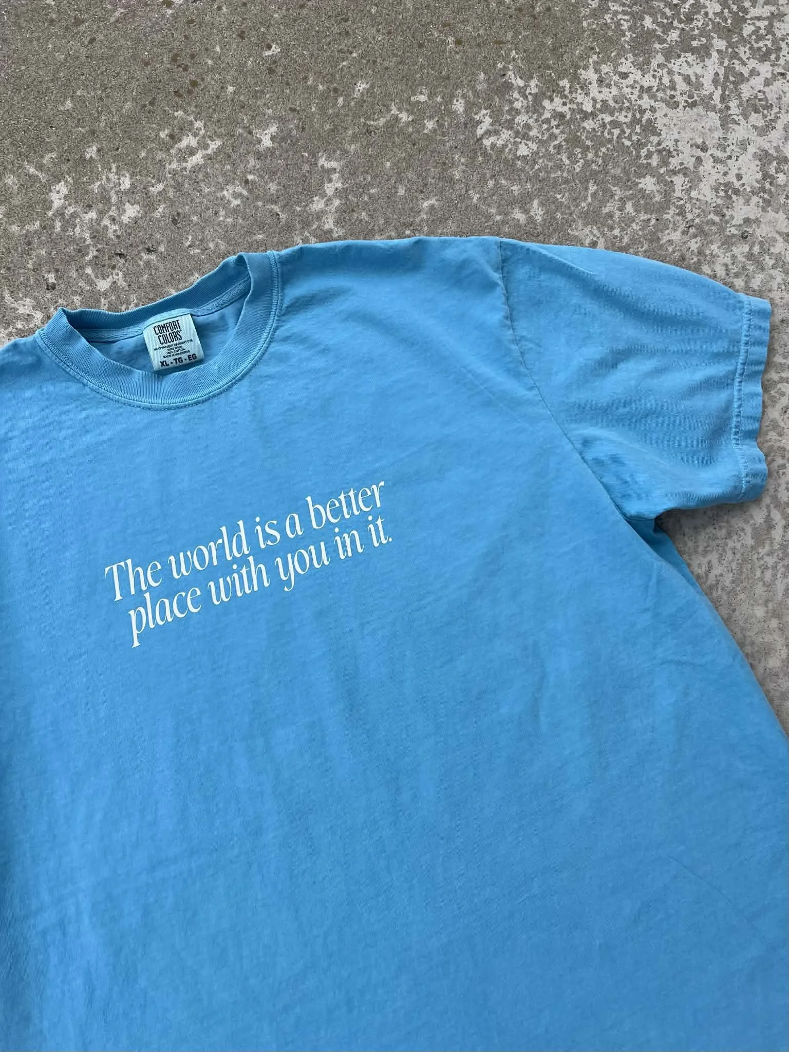 Light blue tee that has white text reading 'the world is a better place with you in it'