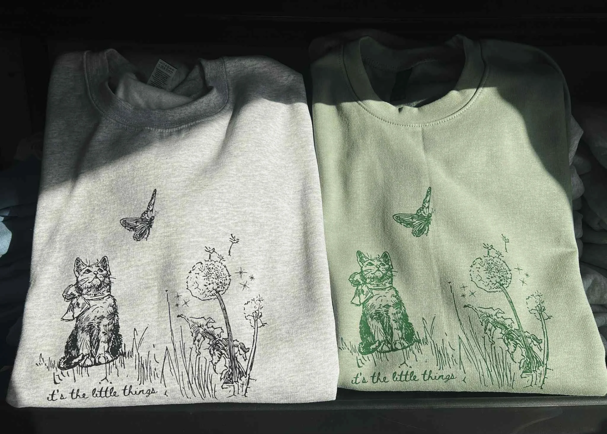 SAGE GREEN AND ASH GRAY SWEATSHIRT WITH ILLUSTRATION OF CAT AND BUTTERFLY WITH TEXT THAT READS 'ITS THE LITTLE THINGS' BELOW