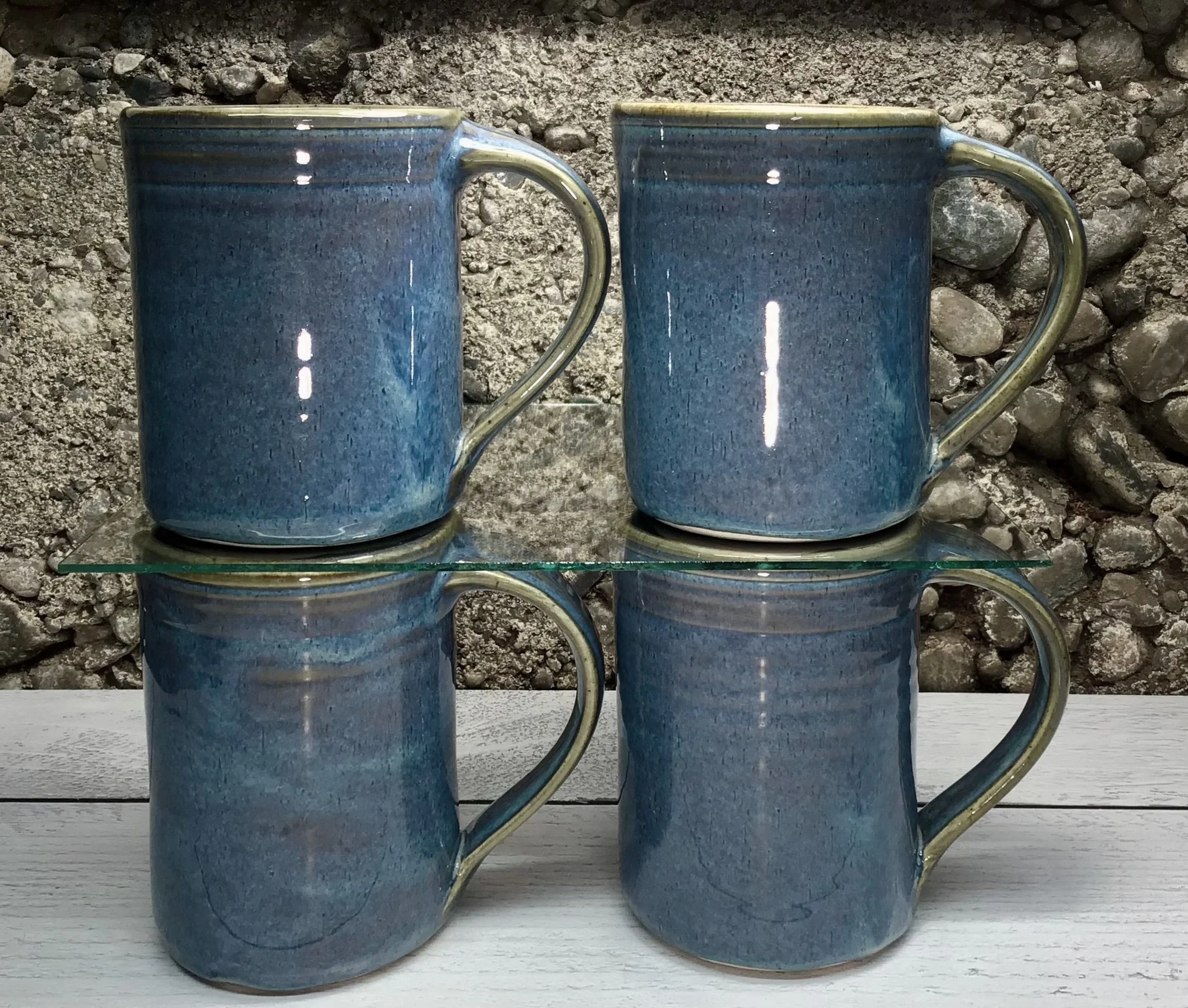 Set of four handmade pottery Twilight Blue mugs stacked on top of each other.. Perfect hot or cold beverage mug holds 14 ounces or more. Made from sturdy stoneware, microwave and dishwasher safe.