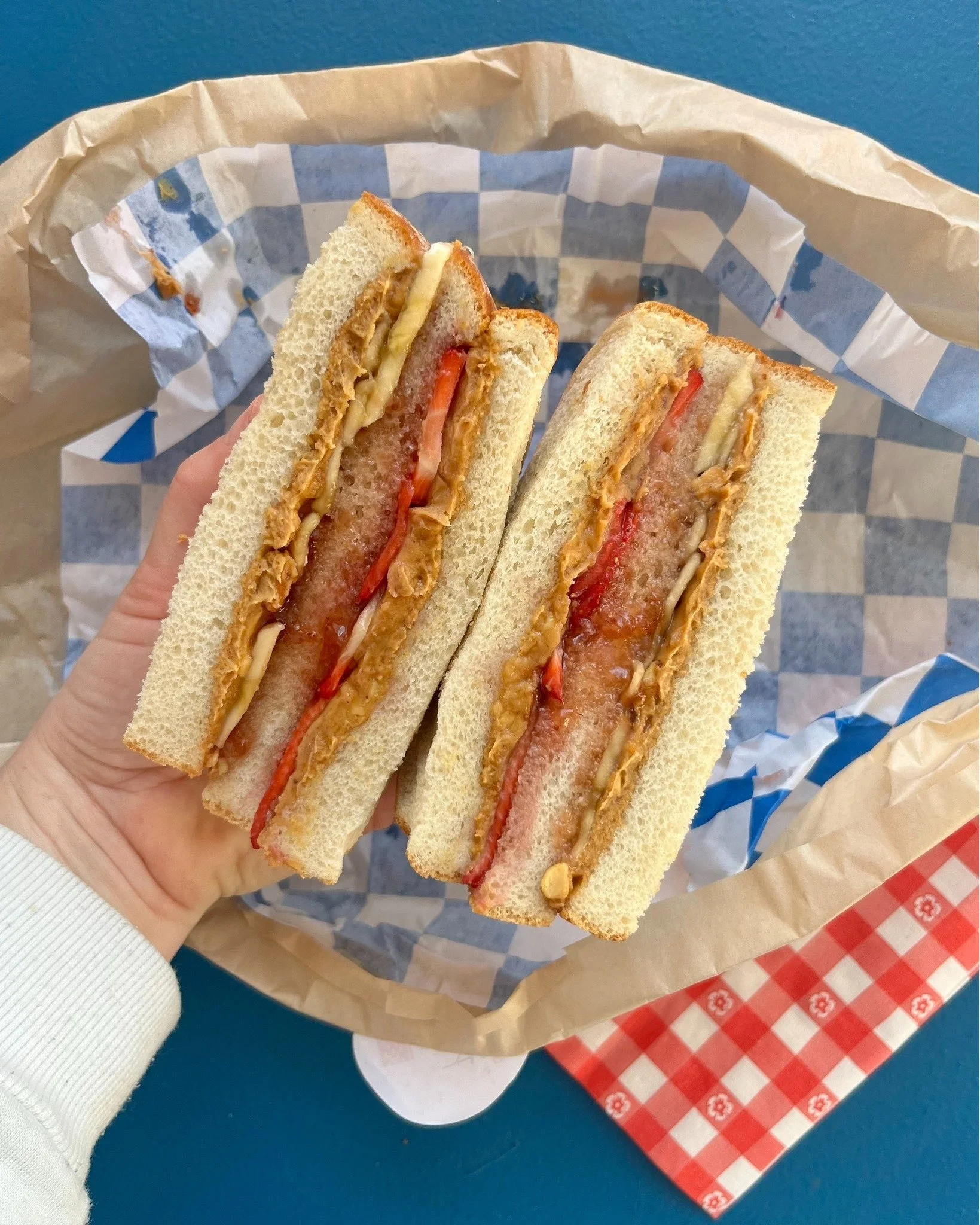 Have you tried our Double Decker PB&amp;J yet? Stacked high with crunchy peanut butter, strawberry jam, bananas, and strawberries on soft white. A childhood favorite, all grown up. 💙 Come see us today, here is the 2/18 GRAB &amp;GO! #ginghammarket