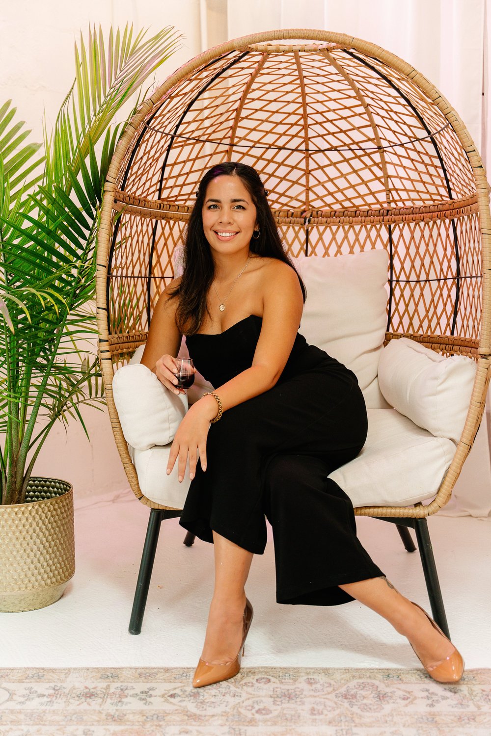 Samantha Zo, founder of BTWN WRLDS, seated in a rattan egg chair