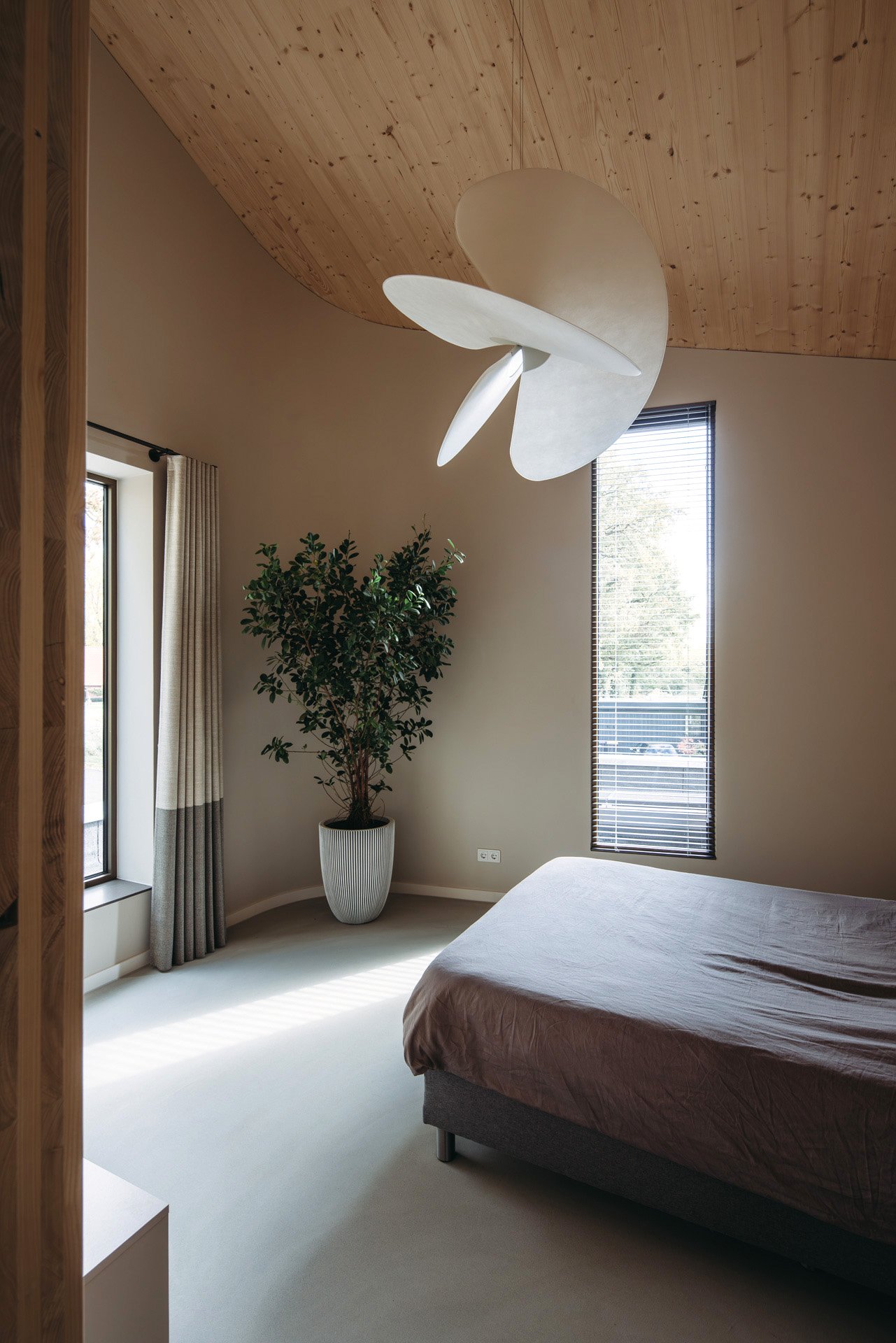 Luxe hoge slaapkamer met blank houten plafond en wand (CLT). en zachte zandkleurige wanden.