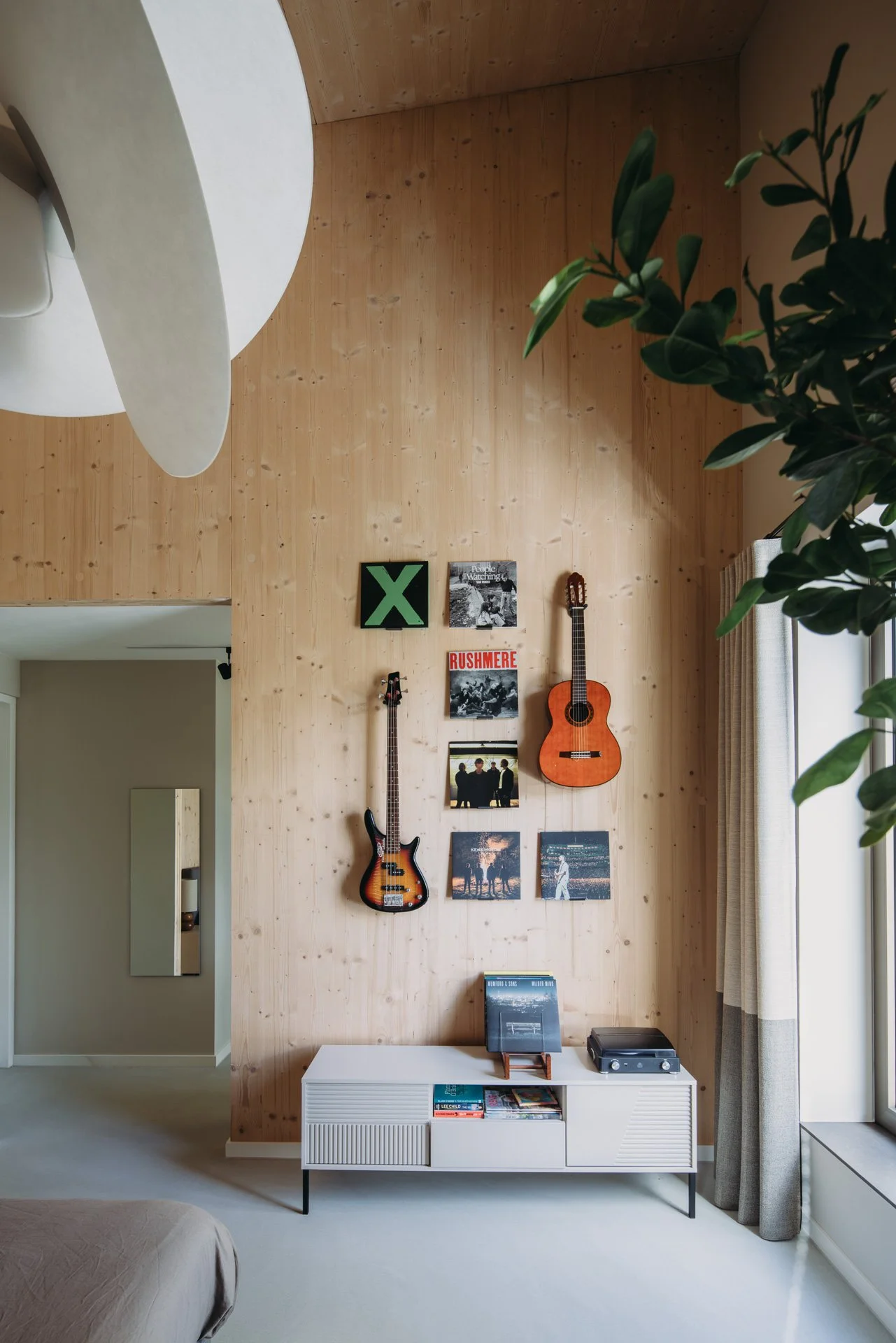 Blank houten wand gedecoreerd met lp hoezen en gitaren.