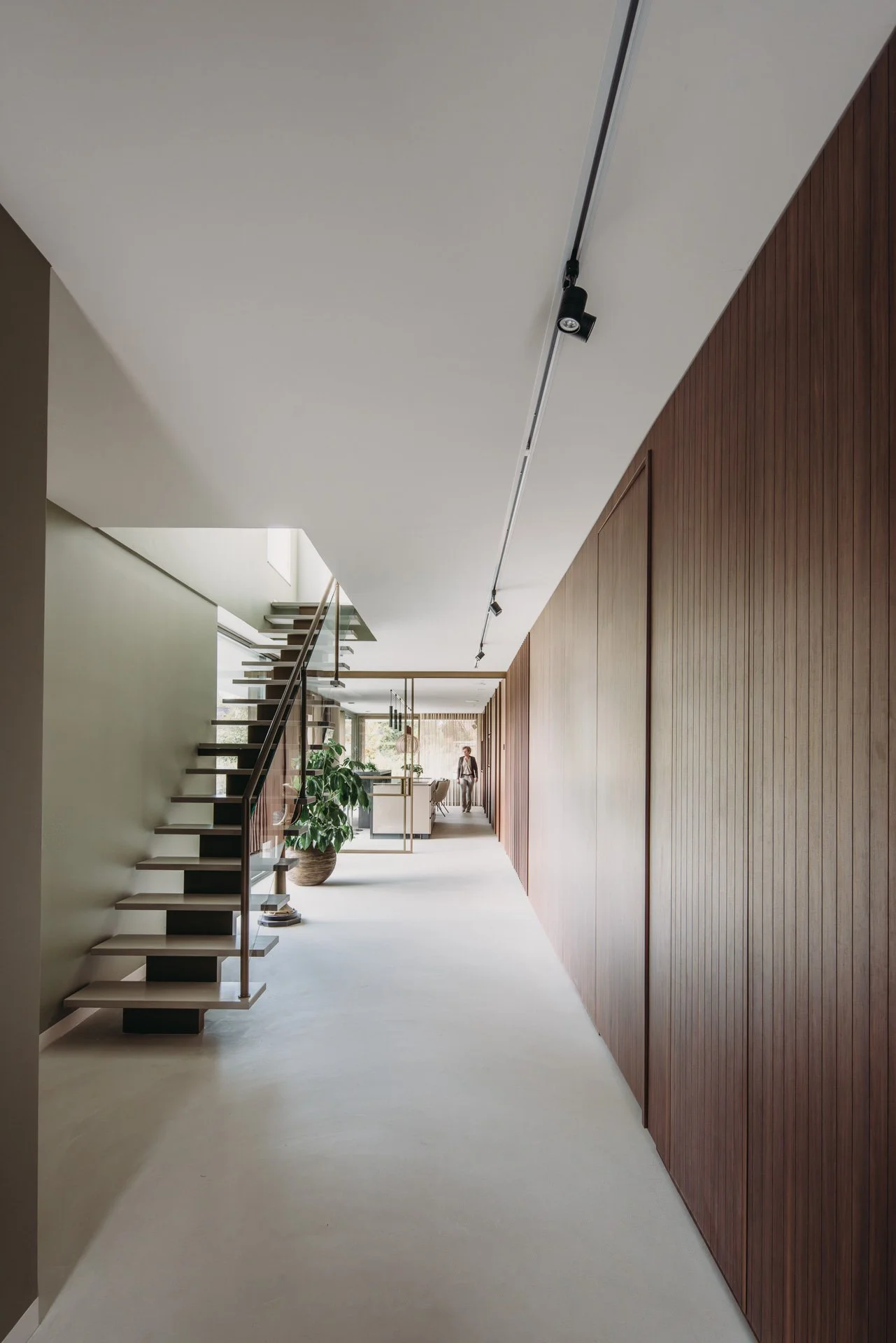 Hal met groene wand, houten kastenwand en open trap naar boven