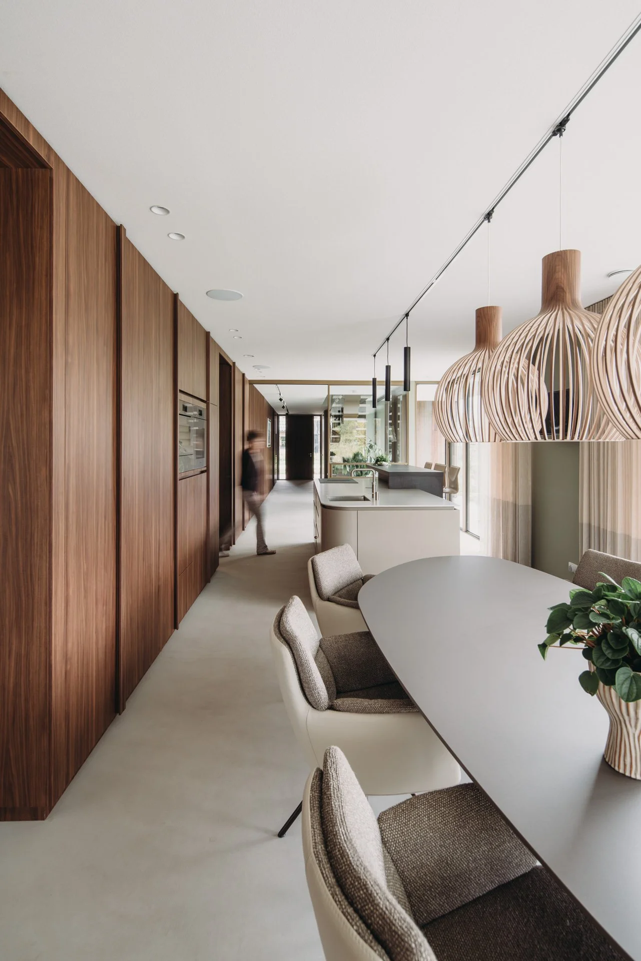 Zicht vanuit keuken naar hal, met lange walnoot houten kastenwand