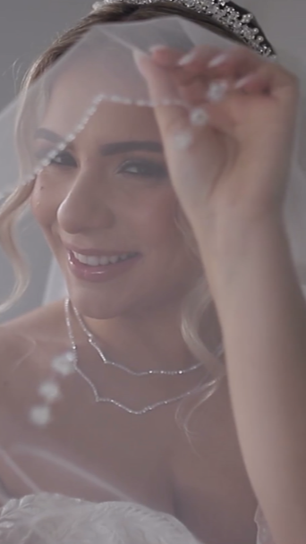 Bridal bride with a tiara, holding a wedding veil, smiling.