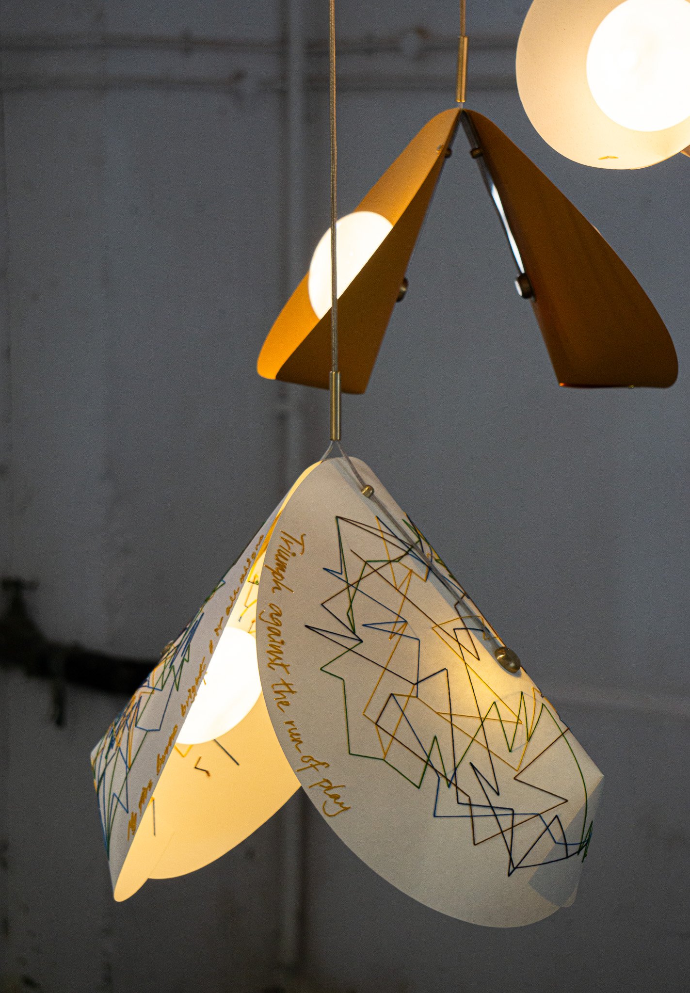 Modern pendant lamps with geometric designs and text on the shades, emitting soft light.