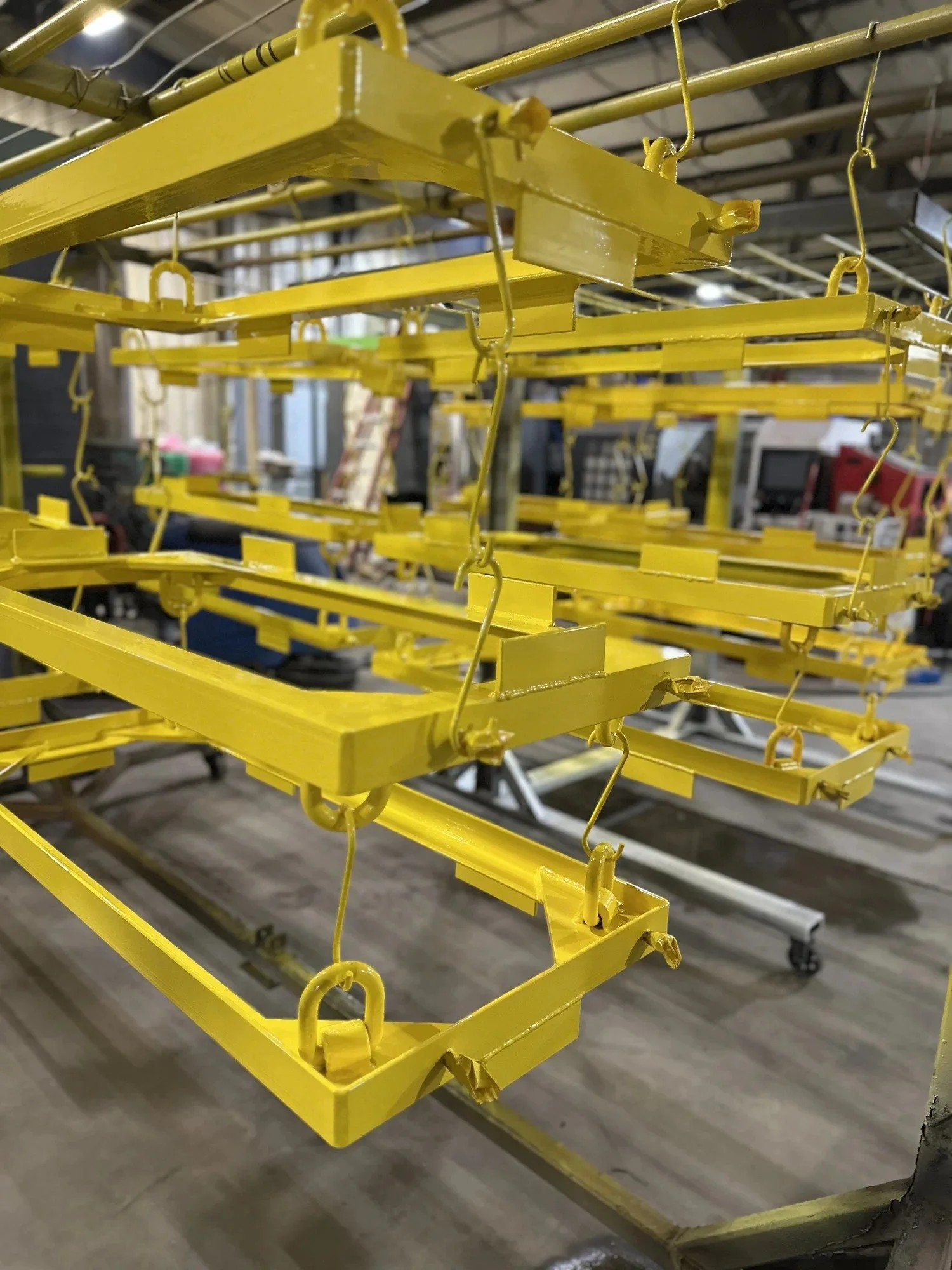 Large fabricated frames hung on the powder coating line at ADK Blast N Coat in Queensbury NY