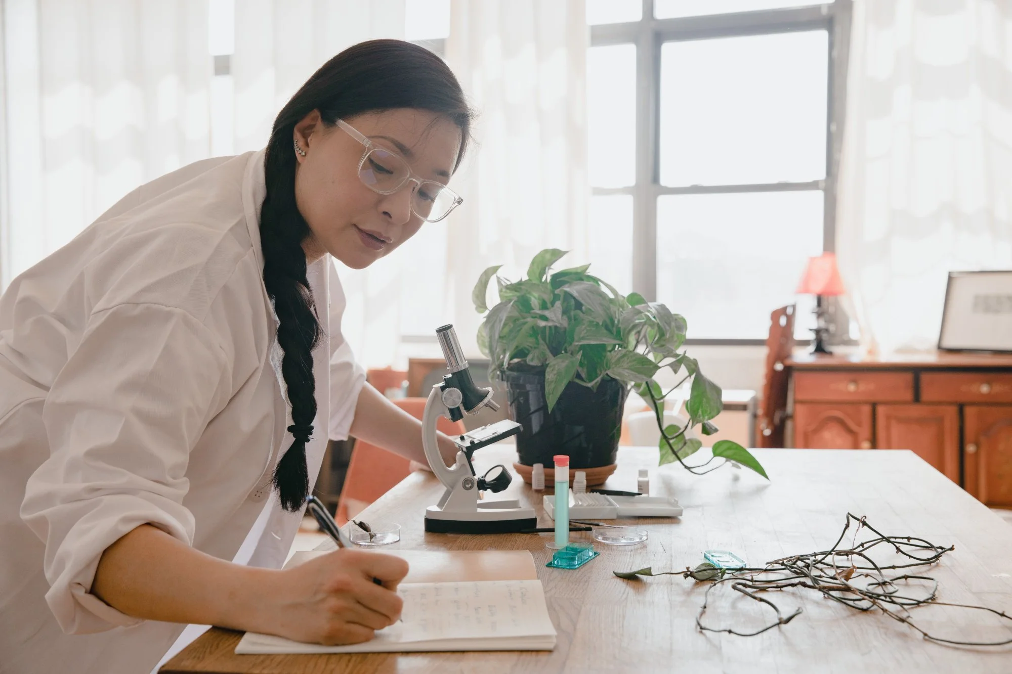 A researcher taking notes at a microscope