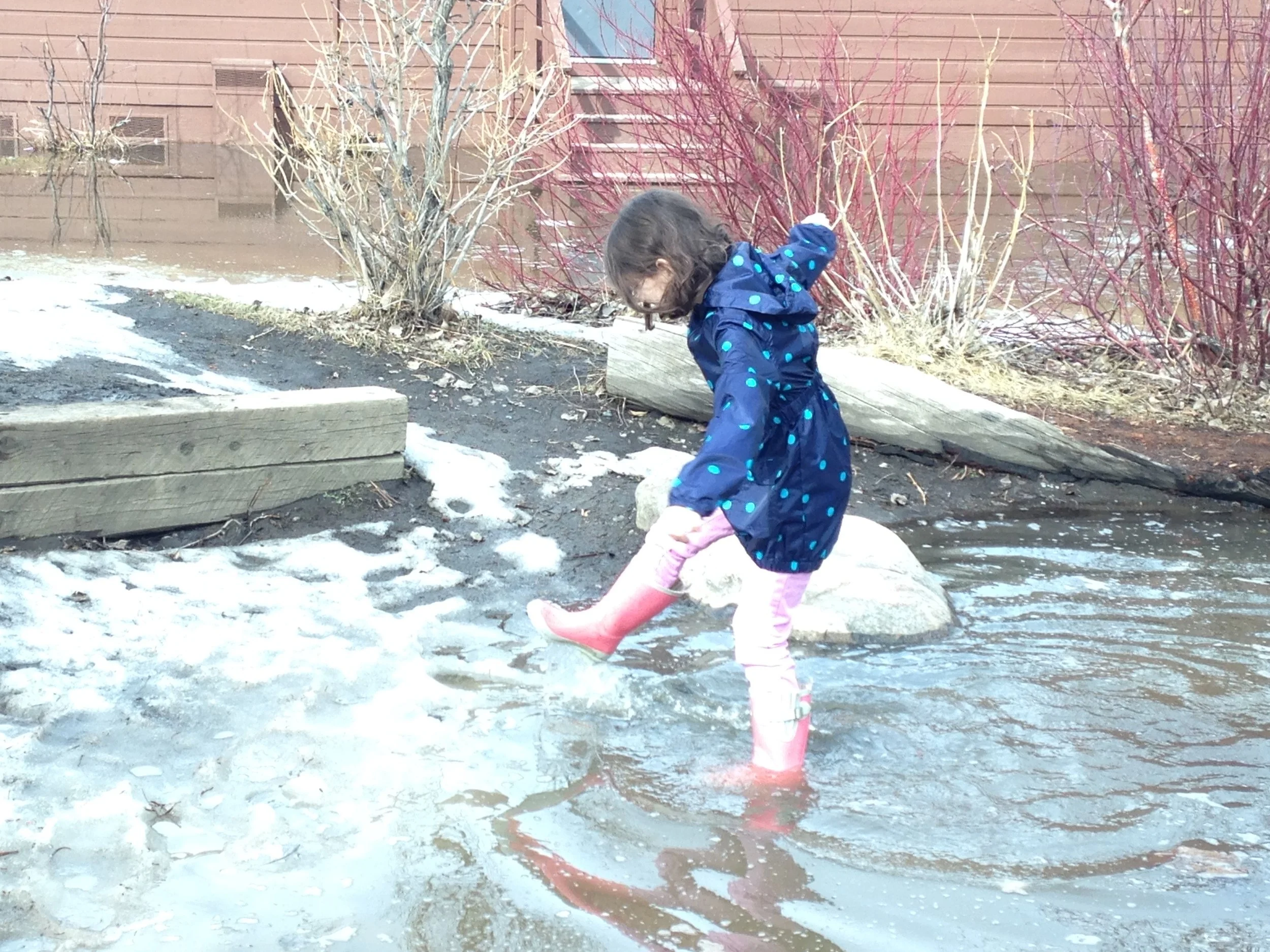Young girl splashing in large puddle