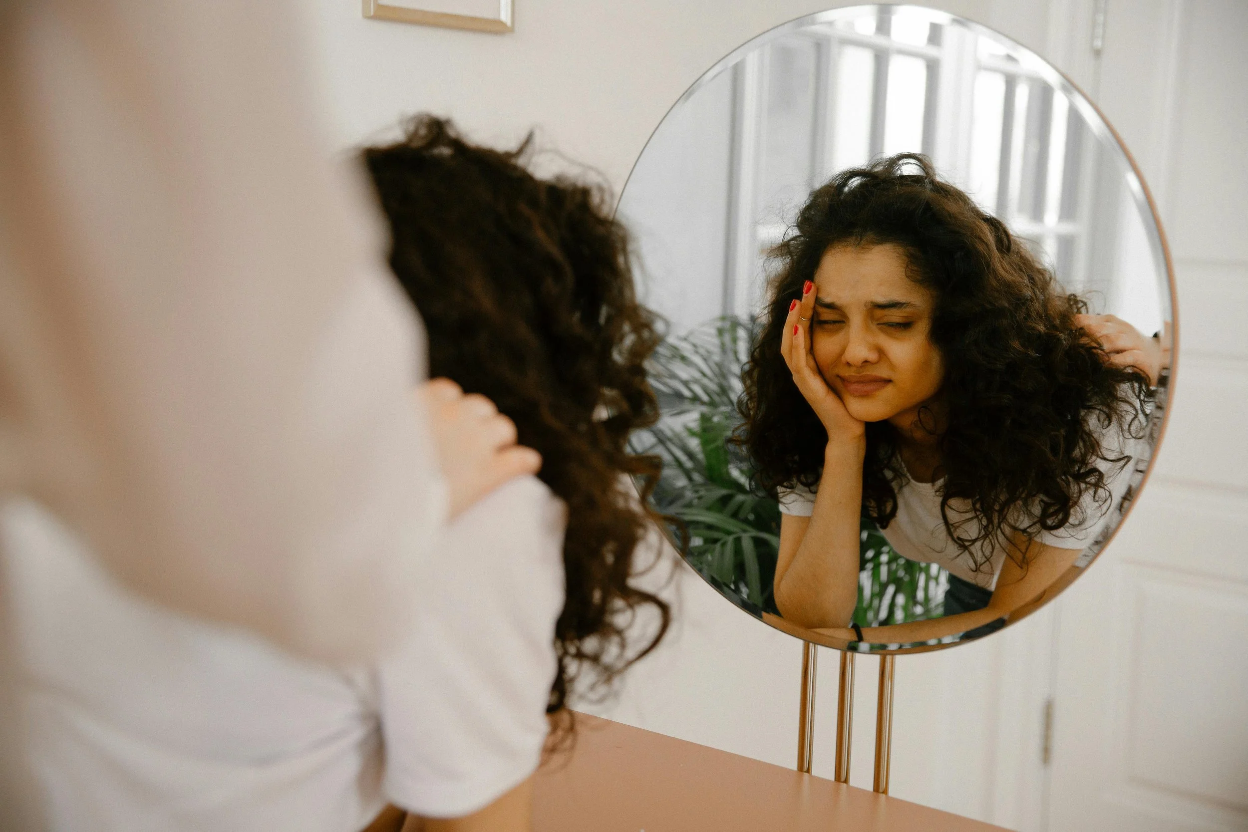 Person looking at themselves in the mirror, thinking "How do I stop hating myself."