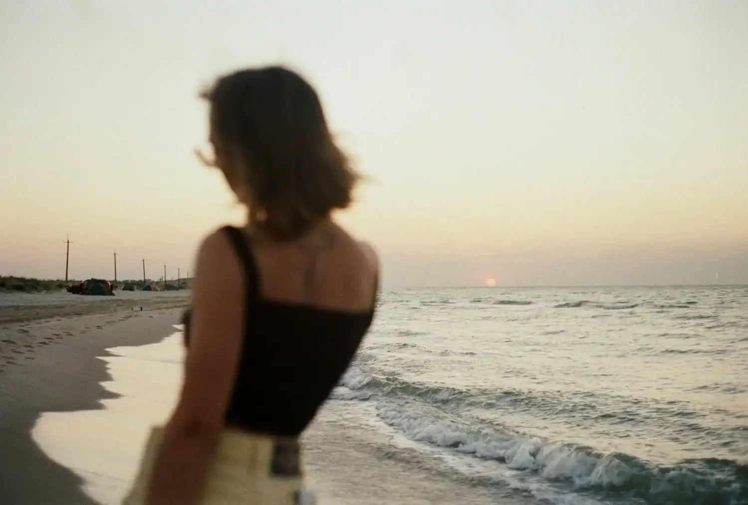 woman standing on a beach at sunset after an online therapy session with everbe therapy