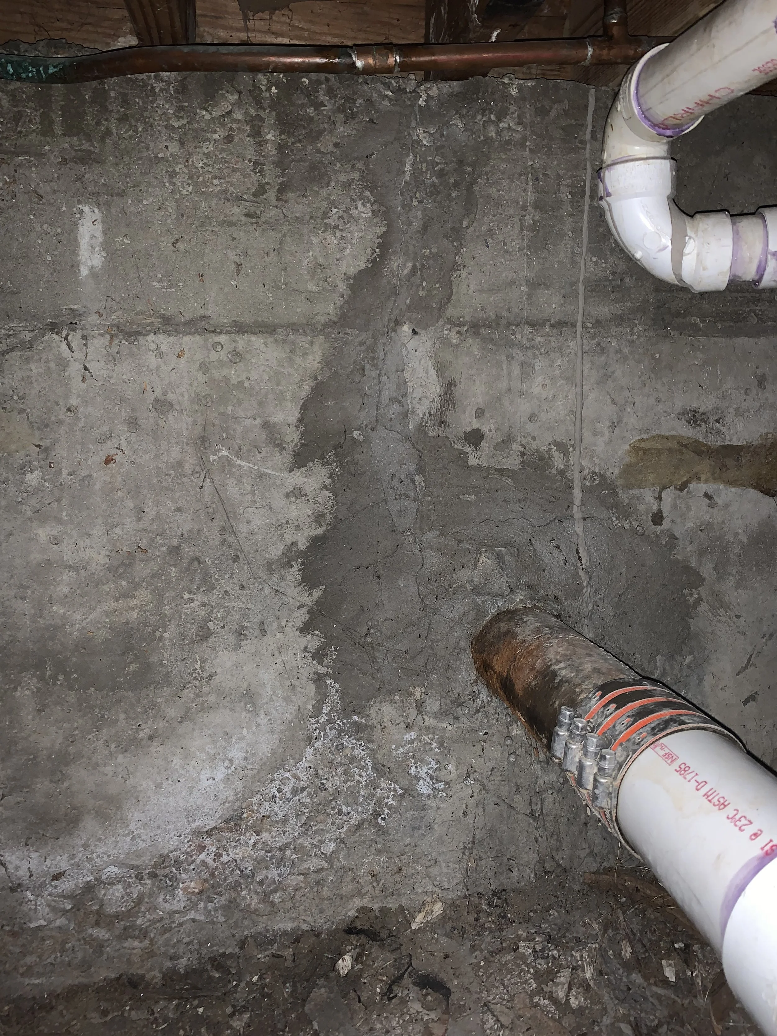 A concrete foundation wall that had a large vertical crack in it with new grout which has been put in the crack to seal it.