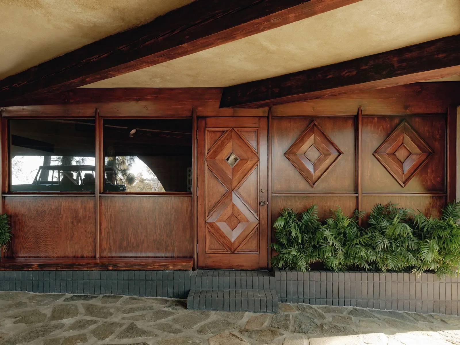 Original Lloyd Wright Jr. geometric-carved wood entry door and wall panels at the De Jonghe Residence, Laurel Canyon; historic residential restoration by Michel Architects, Los Angeles
